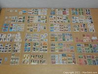 Overview photo of multiple sheets with a large variety of postage stamps arranged in rows on a flat surface.