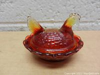 Miniature vintage amber glass chicken shaped ring holder with scalloped dish base and removable lid, textured details on body, comb and tail with color gradient from amber to yellow.