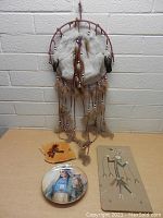 Dreamcatcher hanging on wall with pouch, plate, and wooden plaque displayed below on a table