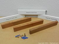 Three new wooden magnetic knife strips displayed on a table with their boxes and mounting hardware.
