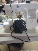Side view of Kenmore sewing machine including foot pedal cable and hard plastic carrying case underneath.