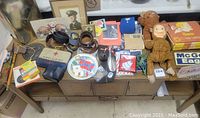 Photo showing entire lot items arranged on a wooden table including toys, belts, framed photo, and assorted memorabilia.