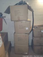 Four stacked cardboard boxes labeled with SKU and size information, containing men's belts