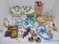 Photo showing full assortment of vintage jewelry and accessories including clutch, necklaces, bracelets, earrings, pins, pearls, and clips arranged on white background.
