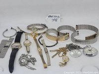 Various watches, watch bands, pocket watches, and necklaces displayed together on white surface.