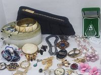 Front view of assorted vintage and modern jewelry items including bracelets, necklaces, pins, earrings, and a black pouch.