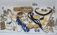 Full overview of the entire jewelry lot displayed on white background, showing various bracelets, necklaces, brooches, and earrings in gold-tone, silver-tone, and blue bead styles