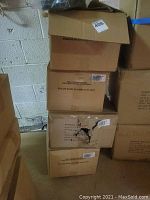 Four stacked cardboard boxes containing the belts packages, some boxes have visible damage and holes.