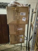 Three cardboard boxes stacked containing new Bit & Biddle ladies belts in tan color, size XL and others, quantity 48 pieces per box.