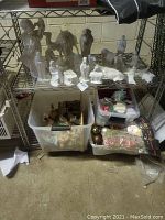 Shelf with ceramic nativity figures arranged, stable visible behind, plastic bins with more decorations and unknown items below.