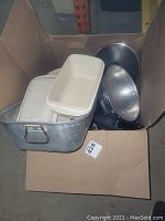 Photo showing cardboard box containing rectangular metal pan and metal mesh strainers.