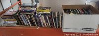 Multiple shelves and a box showing numerous DVD single cases and box sets with varied titles.