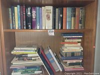 Two wooden shelves filled with hardcover and paperback books, titles visible include various genres such as fiction, non-fiction, and reference.