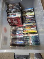 Top-down photo of DVDs arranged in a container showing various titles and genres.