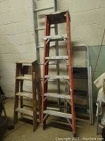 Four ladders positioned against a wall showing their full lengths and conditions.