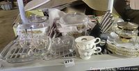 View of set on shelf showing 4 Corningware casserole dishes with glass lids featuring Spice of Life pattern, stacked milk glass egg dishes, silvertone serving dish with warming candle, clear glass salt cellars with spoons on a tray, and black knife block with knives.