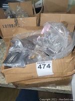 Box of assorted new belt buckles in plastic bags, visible Harley Davidson buckle.