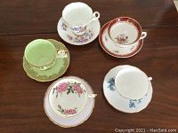 Top view of all five cups and saucers arranged on a brown wooden table
