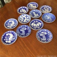 Full set of eleven Royal Copenhagen Mother's Day plaques arranged on wooden surface illustrating cobalt blue ceramic with white decorative figures and floral motifs.