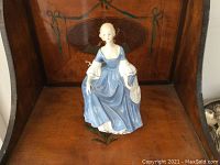 Porcelain Royal Doulton Hillary figurine shown front view, standing on wooden surface.