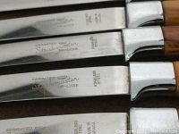 Close-up photo showing the blade engraving 'Steakmaster DE-LUXE', serrated edge, and wood handle.