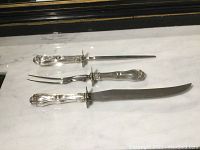 Full set of three pieces—knife, fork, and sharpening steel—laid out on white marble surface