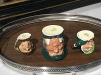 Photo of three Royal Doulton figurines from a top-down angle on a silver tray showing painted details and bases.