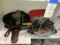 Photo of two cast iron skillets, vintage food chopper, silicone muffin mold on metal baking pans, and assorted kitchen utensils including spatulas, pizza cutter, tongs, and grater.
