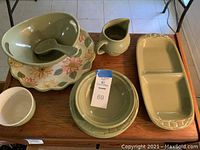 Top view of the full set displayed on wooden table showing plates, bowls, spoon, pitcher, and divided plate.