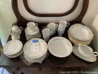 Full set arranged on wooden surface showing multiple plates, cups, saucers, creamer, sugar bowl, gravy boat, and serving bowl.