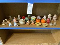 Multiple assorted salt and pepper shakers on wooden shelf, including animal and vegetable designs.