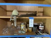 Wood shelf with the beehive wind chime, candles in glass jars, wax mixer melts, assorted candle holders.