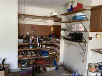 Garage shelving filled with various tools, paint cans, hardware boxes, and extension cords.