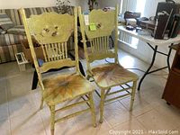 Pair of light green hand painted wooden chairs with ornate press back and sunflower painted seats