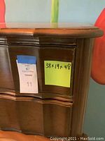 Close-up of chest corner with size labels showing approximate dimensions 38x19x48 inches. Medium wood finish with some wear visible.