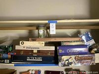Shelf with assorted boxed board games including Backgammon, Pictionary, Cranium, Pathfinder card game, and others.