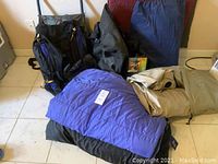 Photo showing the two backpacks, blue sleeping bag, green foam pad, air mattress, and gear bag laid out on floor