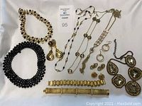 Full view of entire jewelry lot showing necklaces, bracelets, earrings spread out on white background.