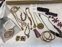 Full view of assorted Mary Kay jewelry including necklaces, bracelets, earrings, and rings in pink and purple tones