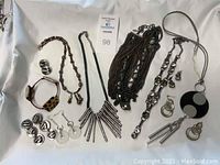 Overview of all jewelry pieces in the lot including necklaces, bracelets, rings, and earrings arranged on a white cloth.
