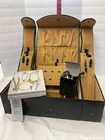 Open Joy Mangano jewelry box displaying beige interior lining with multiple compartments and Mary Kay jewelry on a smaller white jewelry box inside.