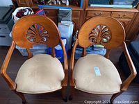 Photo showing both wood side chairs with carved back and beige fabric seats from front angle