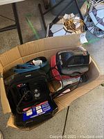 Craftsman wet dry vacuum and MVP air compressor inside a cardboard box with blue heavy duty cords and other accessories.