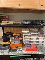 Image showing small boom boxes on a shelf with various labeled plastic containers underneath and other hardware items.