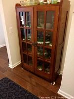 Full view of oak display cabinet showing front glass paneled double doors and contents inside.