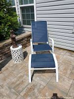 Adjustable patio chair with matching ottoman and white drum table on patio tiles
