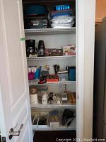 Photo of closet shelves showing various kitchen items including coffee maker, hand mixer, knives, plastic containers, and disposable trays.