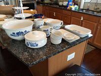 Photo shows full set of Pfaltzgraff blue floral patterned ceramic serve ware on kitchen counter, including bowl, casserole dishes, soup bowls, utensil holder, and baking dish.