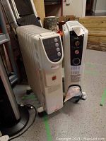 Two white oil-filled radiator style heaters standing side by side on floor, showing overall size and form.