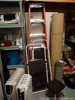 Overall view of lot showing 6 foot Werner ladder alongside multiple Cosco step stools and other miscellaneous items in garage.